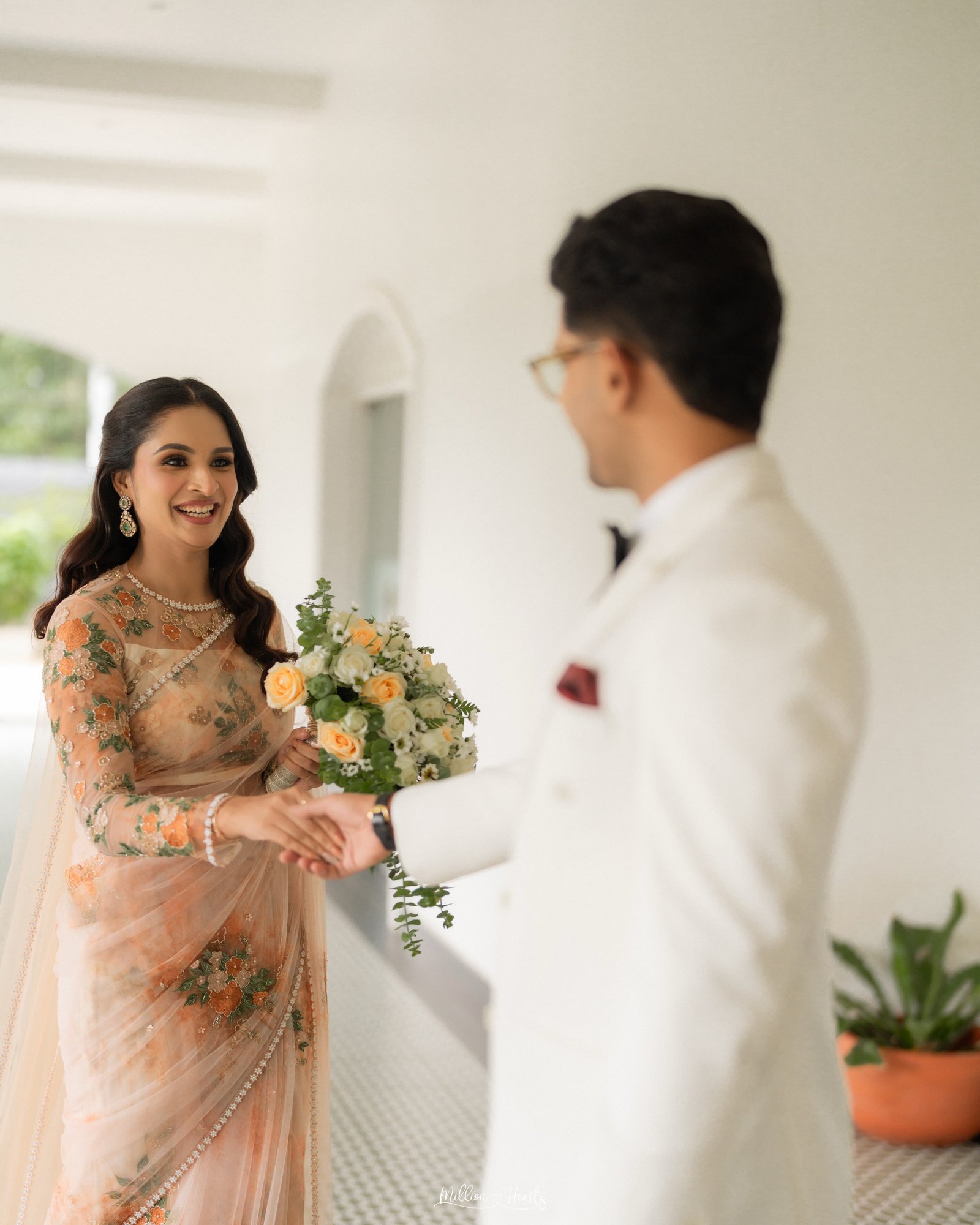 A couple smiling at each other in traditional ivory attire